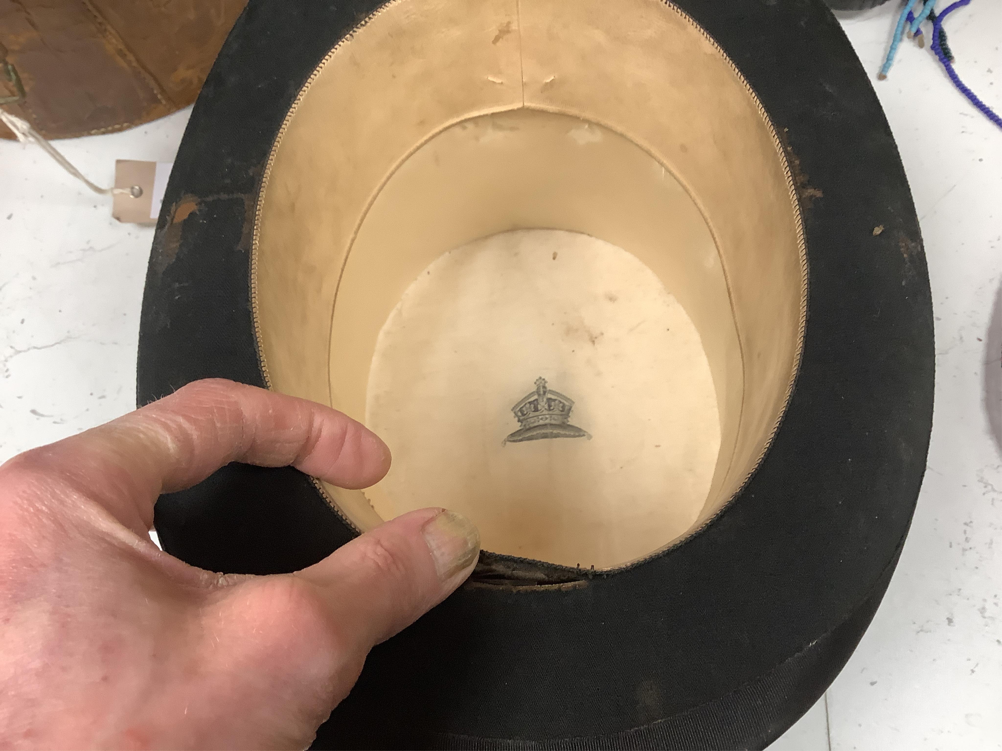 A gentleman’s black silk top hat with a black felt band and, cream silk lining, together with a brown leather case, hat height 17cm. Condition - silk brim worn in various places, leather case very poor